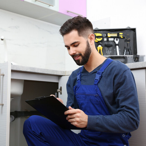 Male plumber with clipboard near kitchen sink